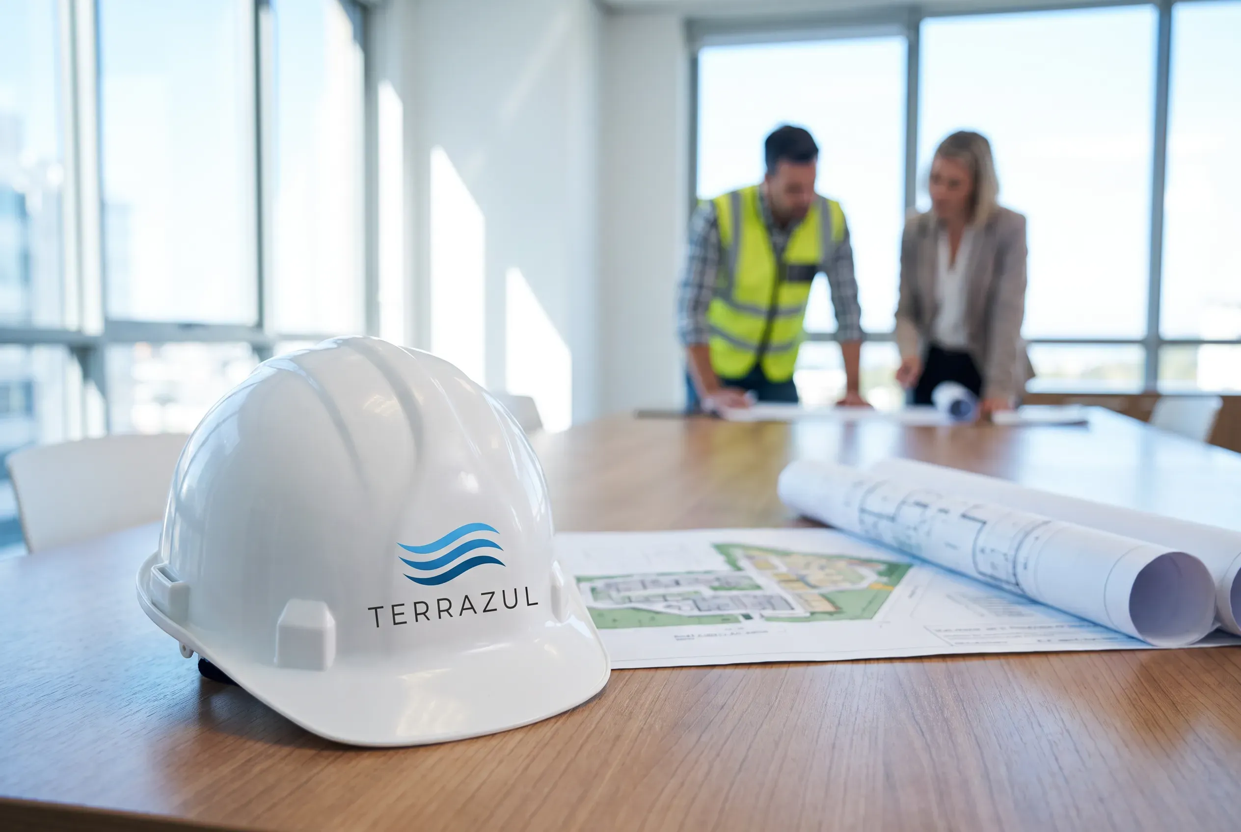 Casco blanco con el logo de TERRAZUL sobre planos de obra, en una sala de reuniones